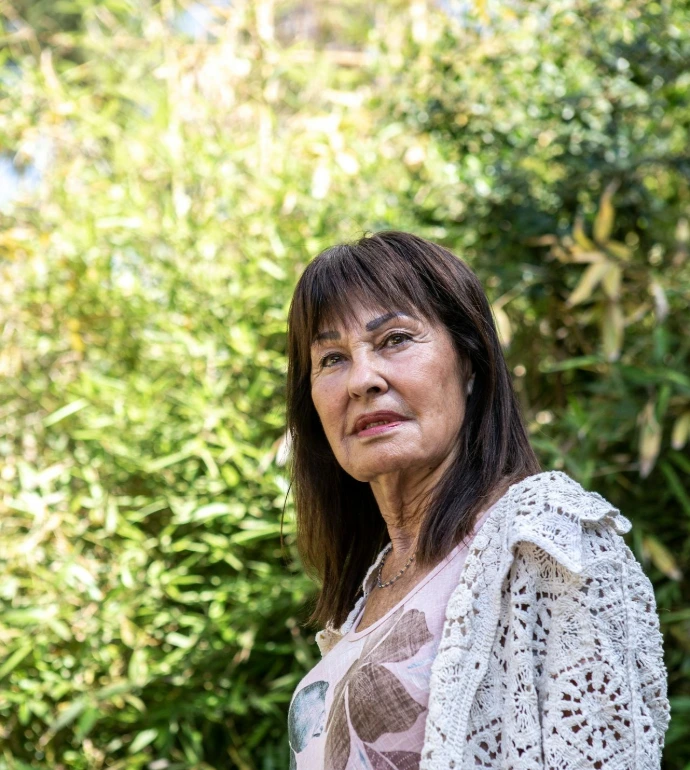 A woman standing in front of some bushes